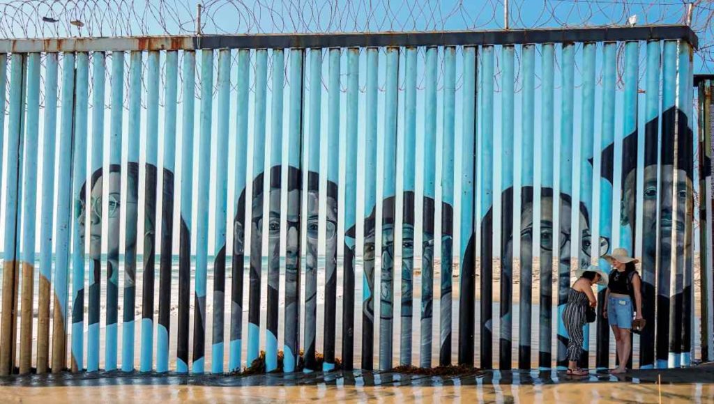 Muro entre México y EU se ilumina con los rostros de migrantes deportados